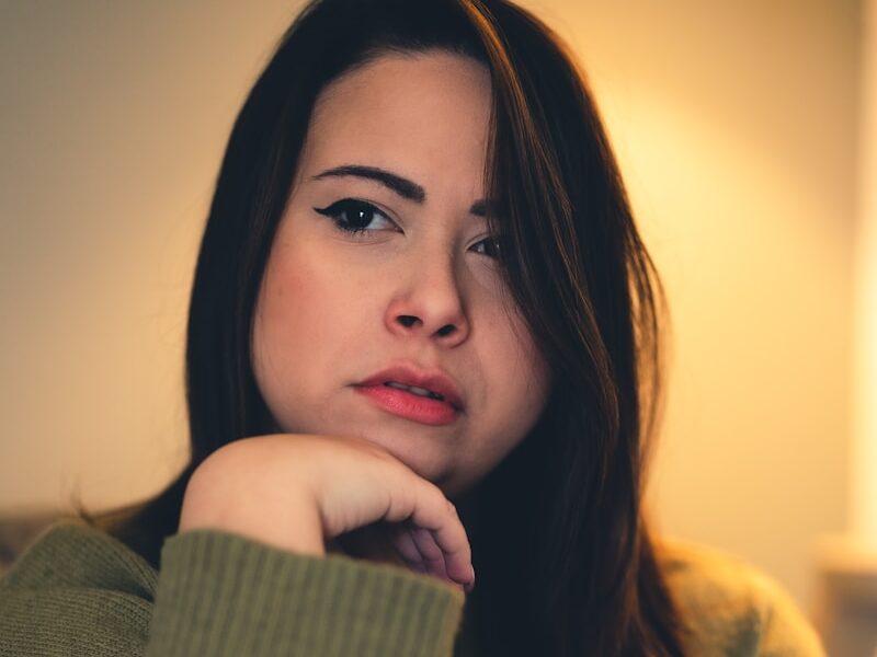 a woman sitting on a couch with her hand on her chin