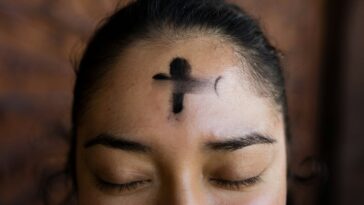 woman with black cross tattoo on her face