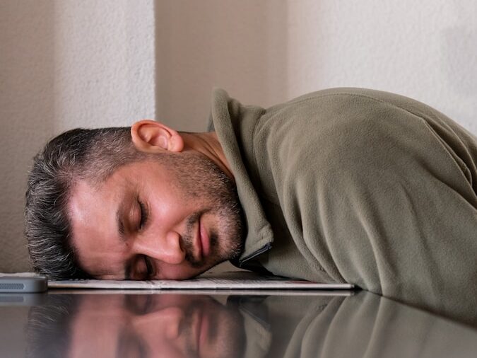 A man is sleeping on the floor with his head on a laptop