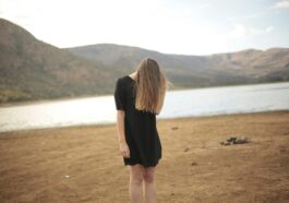 woman in black dress standing in front of lake