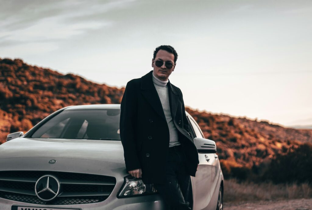 a man standing next to a car on a dirt road