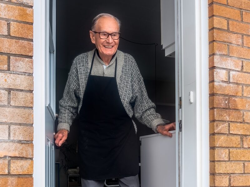 man in black vest and black dress pants standing beside white wooden door