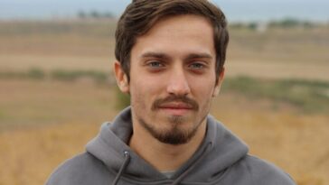 man in gray hoodie standing on field during daytime
