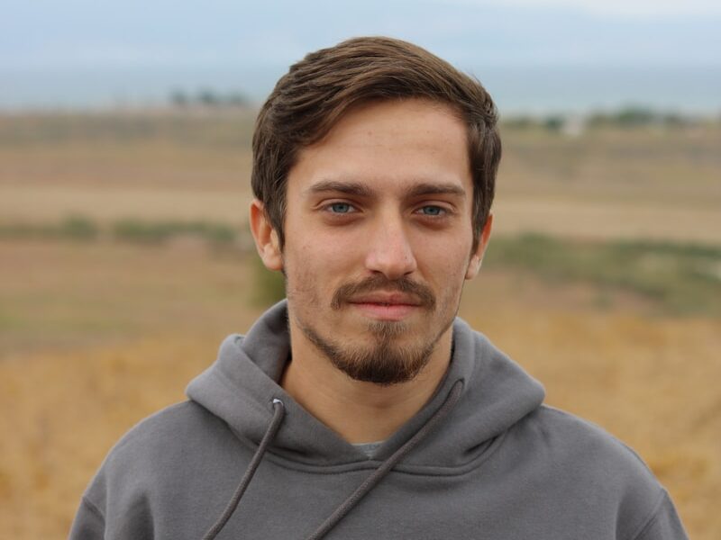 man in gray hoodie standing on field during daytime