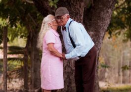 A man and a woman standing next to a tree
