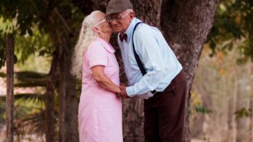 A man and a woman standing next to a tree