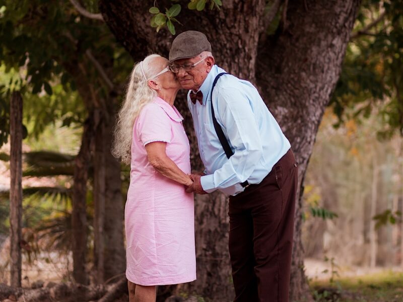 A man and a woman standing next to a tree