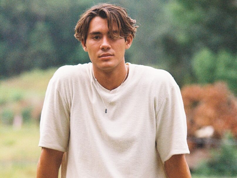 man in white crew neck t-shirt and black pants sitting on rock during daytime