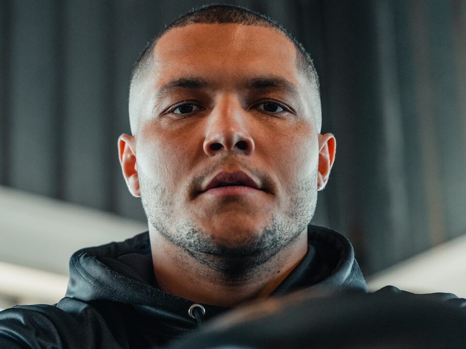A man wearing a black jacket and boxing gloves