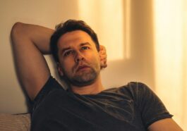 a man laying on top of a couch next to a wall