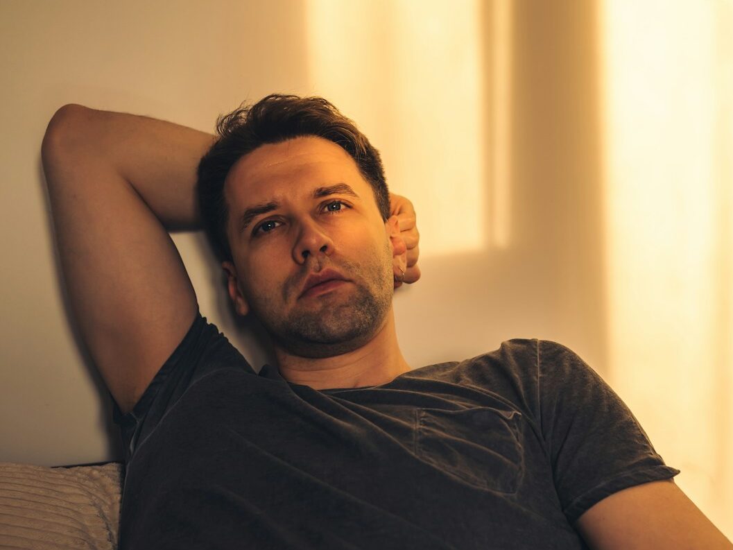 a man laying on top of a couch next to a wall