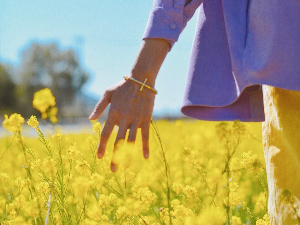 person in brown long sleeve shirt standing on yellow flower field during daytime