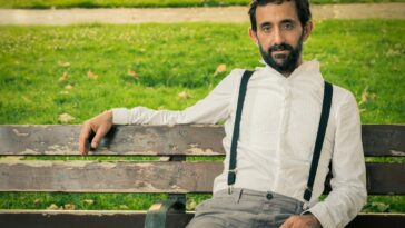 man wearing white dress shirt sitting on outdoor bench