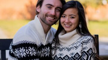 man in white sweater hugging woman in black and white floral scarf