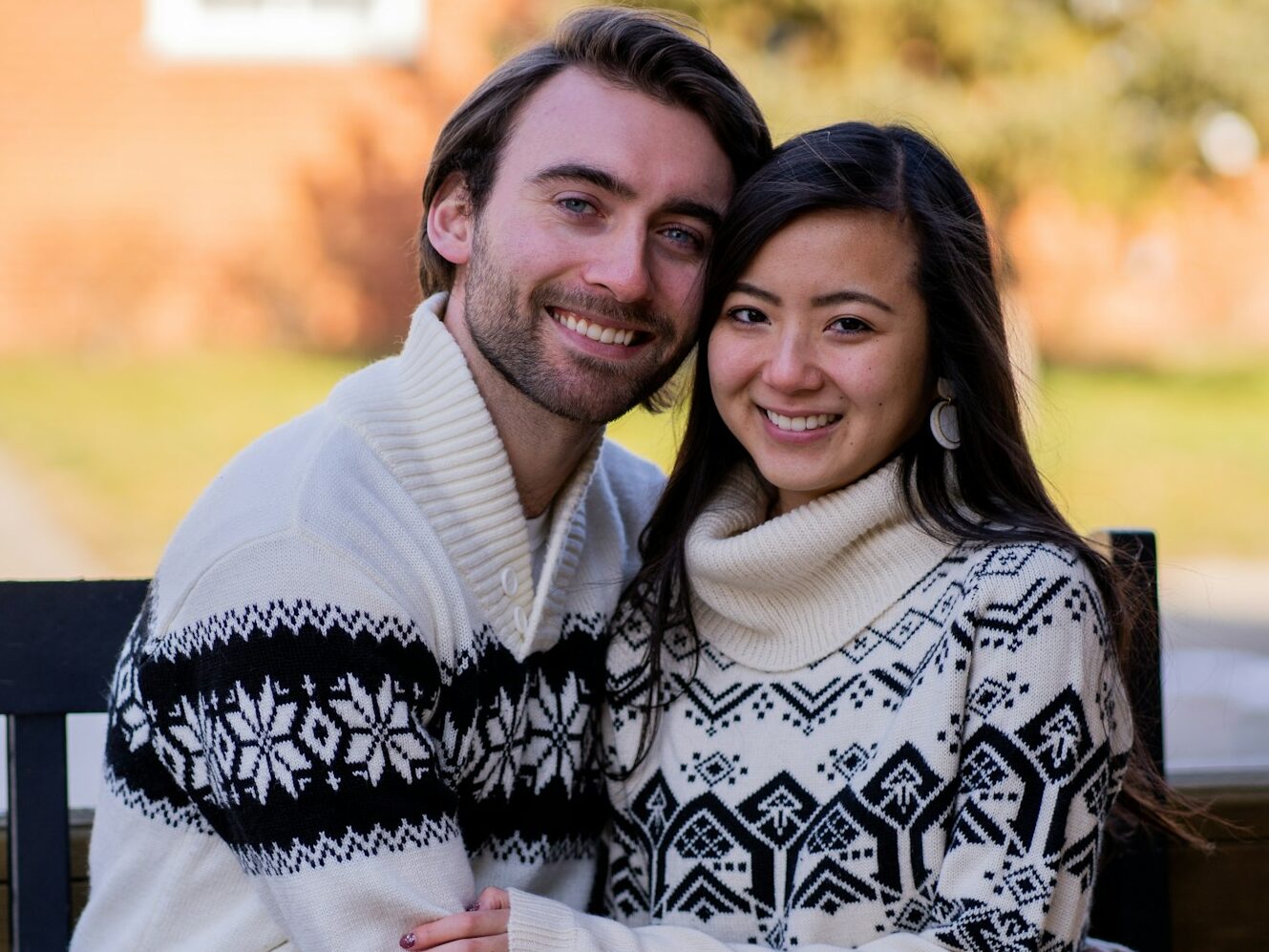 man in white sweater hugging woman in black and white floral scarf