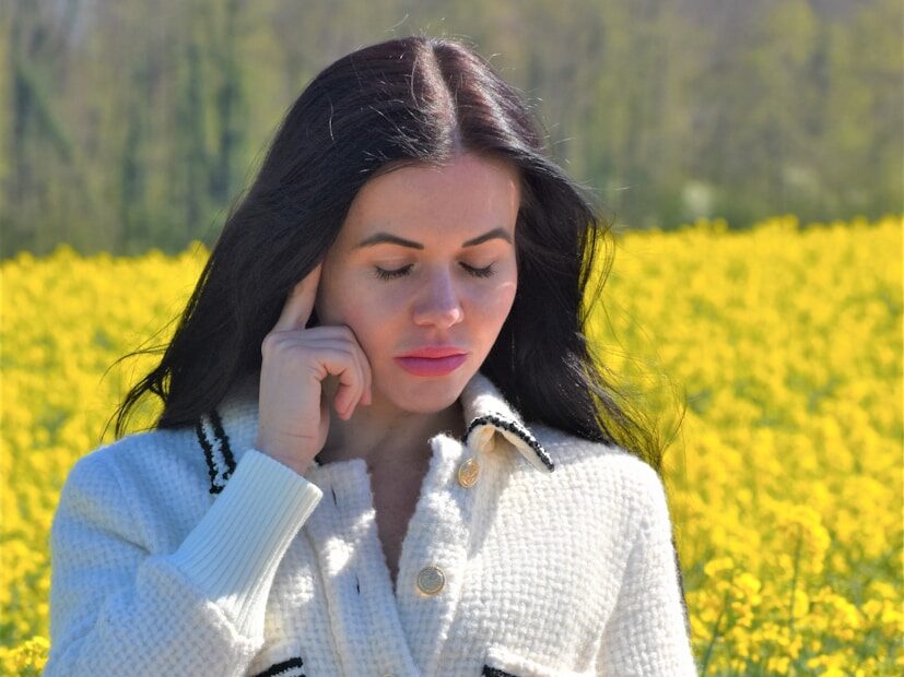 A woman standing in a field of flowers talking on a cell phone