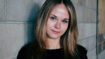 woman leans on gray concrete wall