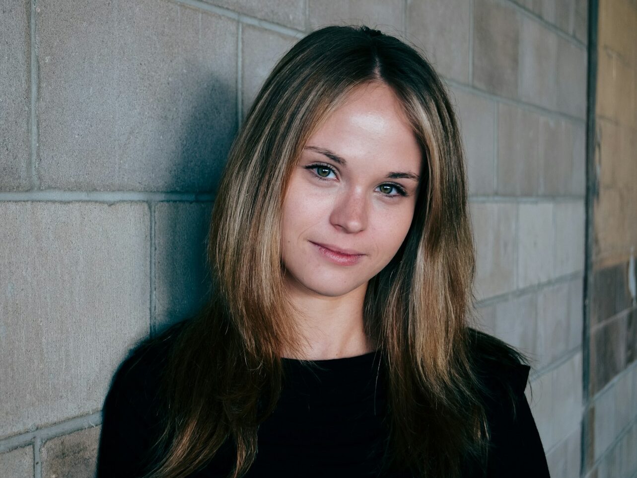 woman leans on gray concrete wall