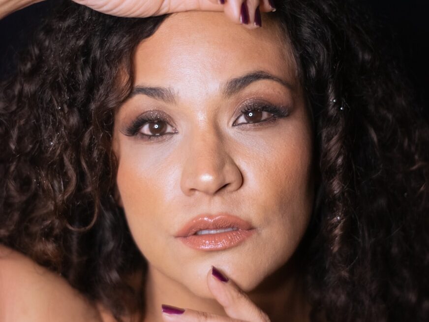 a woman with long curly hair posing for a picture