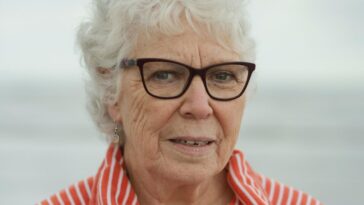 An elderly woman smiles at the camera.