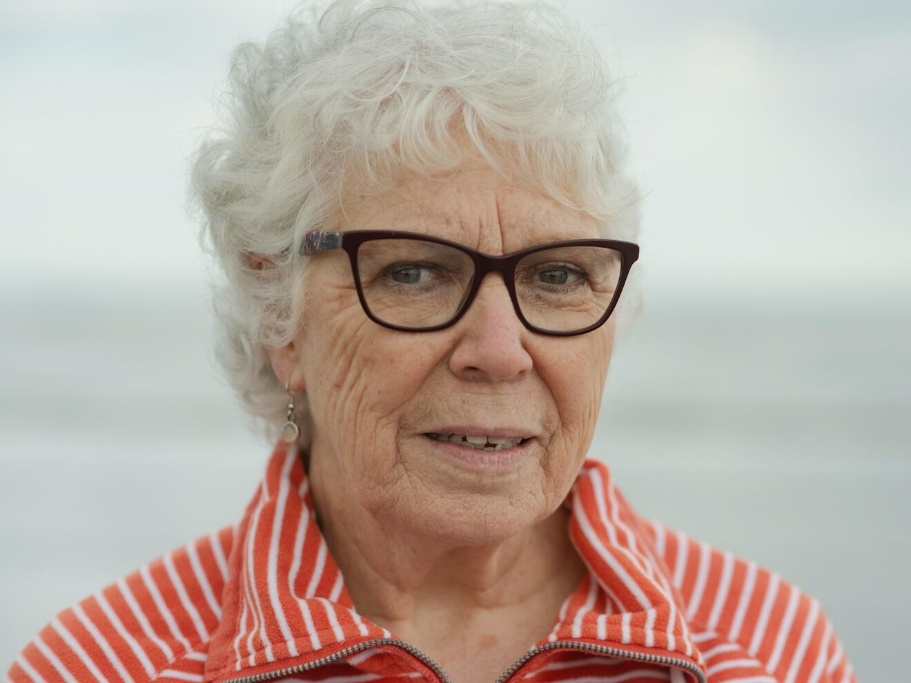 An elderly woman smiles at the camera.