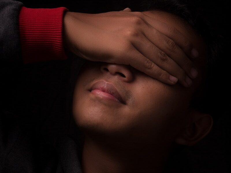 man covering his eyes