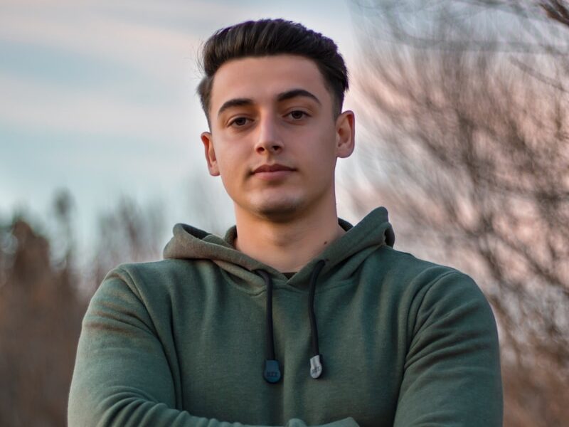 man in green hoodie standing on blue metal railings during daytime