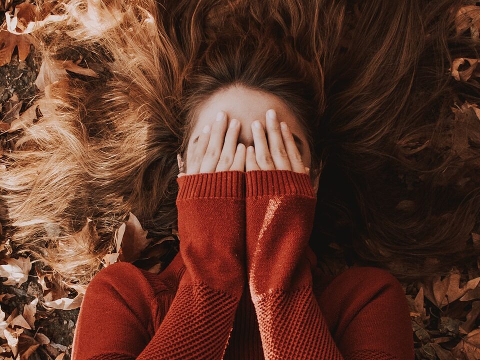 a woman laying on top of a pile of leaves