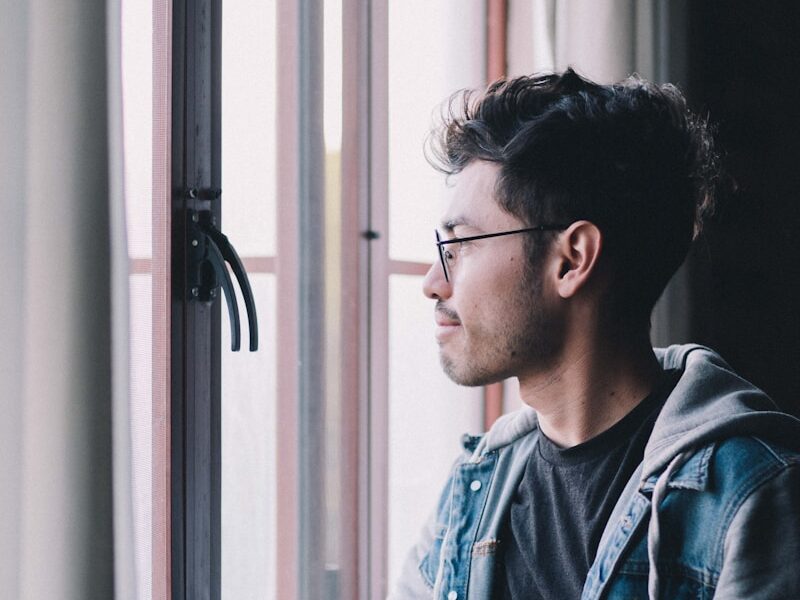 man in blue denim jacket wearing black framed eyeglasses