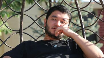 a man sitting in a hammock with his finger in his mouth