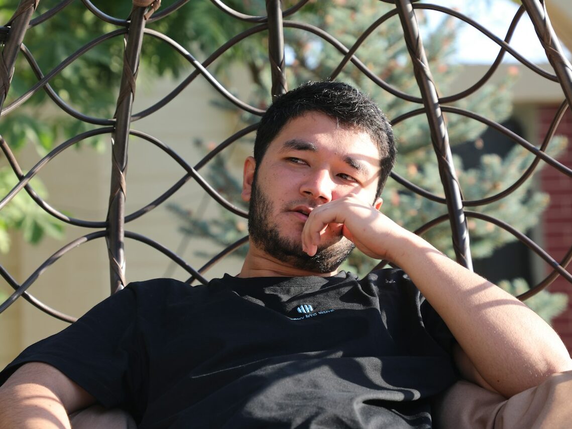 a man sitting in a hammock with his finger in his mouth