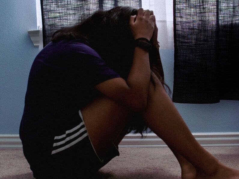 a woman sitting on the floor with her head in her hands
