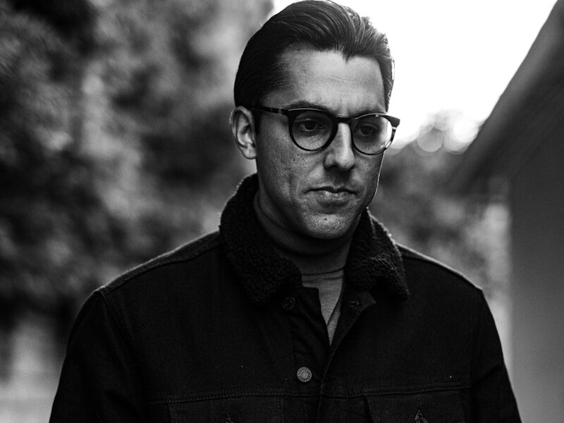 man in black button up jacket wearing black framed eyeglasses
