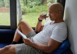 a man sitting on a blue couch looking out a window