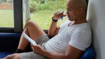 a man sitting on a blue couch looking out a window