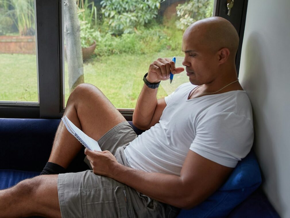 a man sitting on a blue couch looking out a window