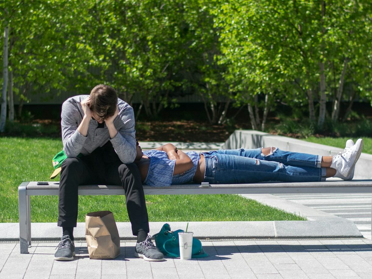 man sitting on white metal bench during daytime