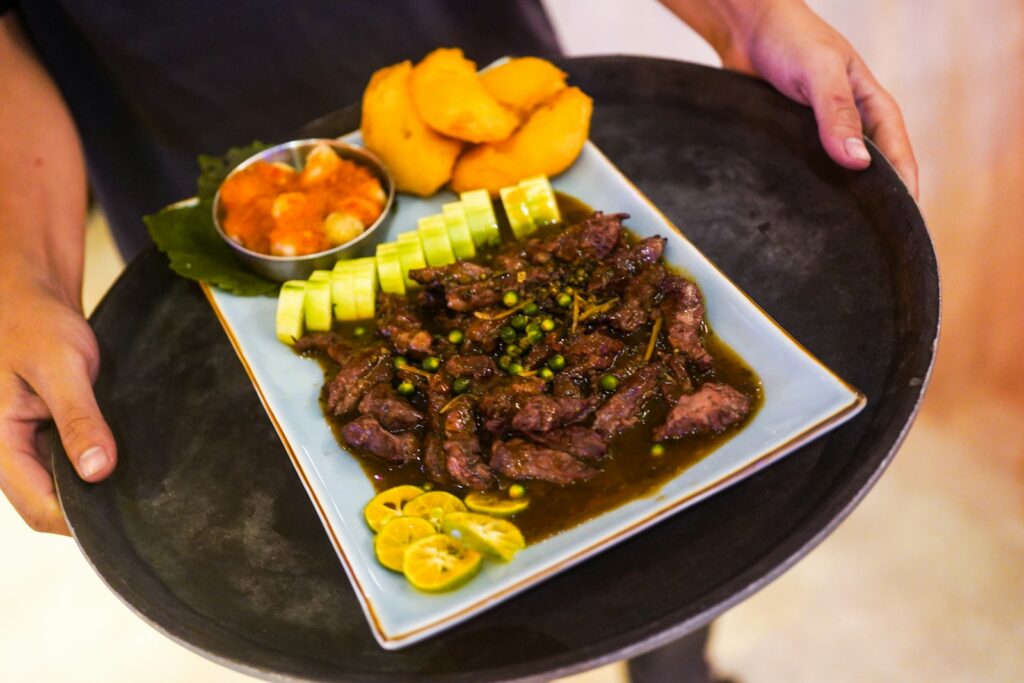 cooked meat with sliced lemon on black ceramic plate