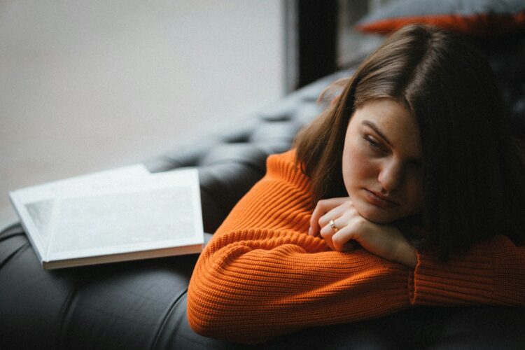 a woman laying on a couch with a book