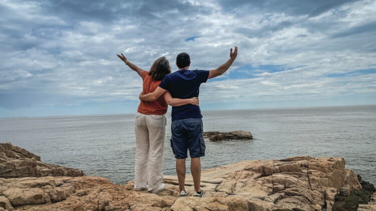A couple of people standing on top of a rock