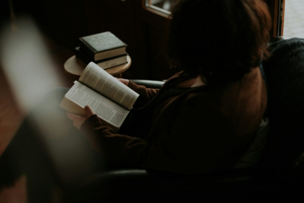 woman reading book on sofa