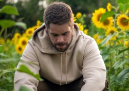 man in white hoodie sitting on green grass field