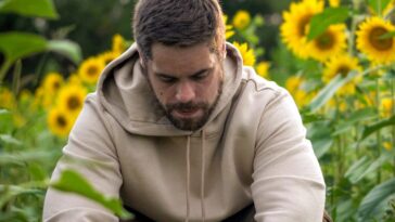 man in white hoodie sitting on green grass field