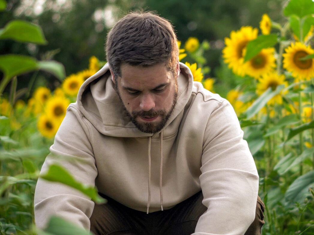 man in white hoodie sitting on green grass field