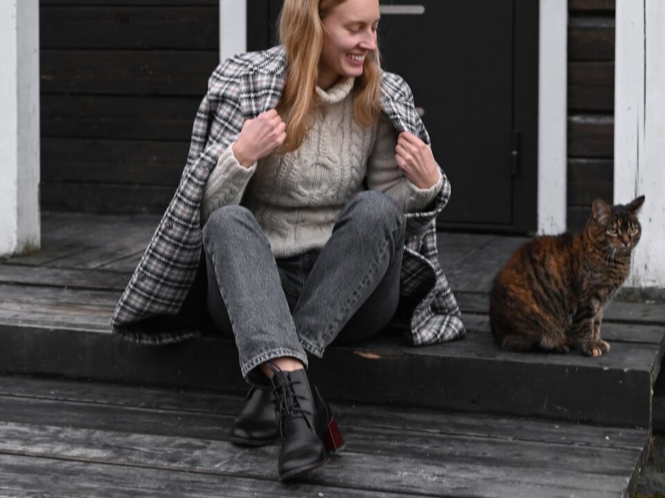 a woman sitting on a porch with a cat
