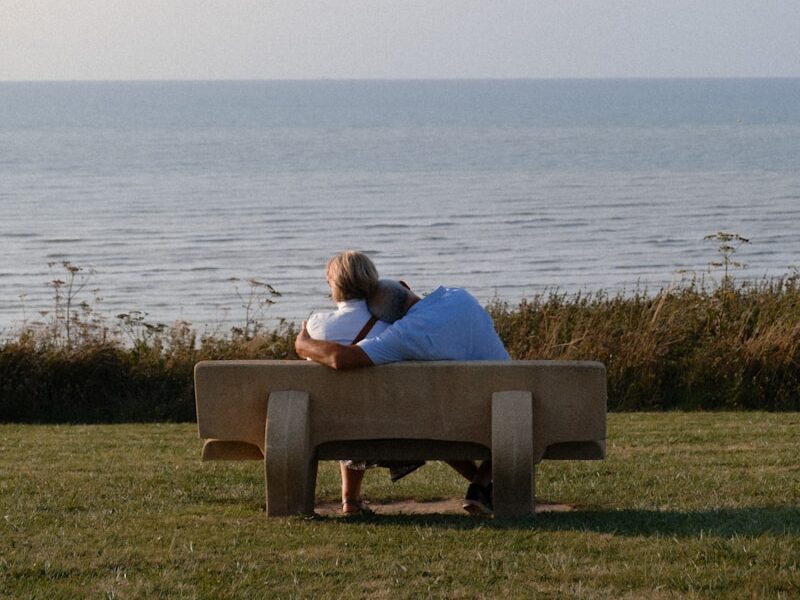 A man sitting on a bench looking at the ocean