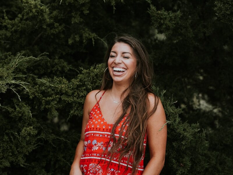 woman laughing while standing near tree