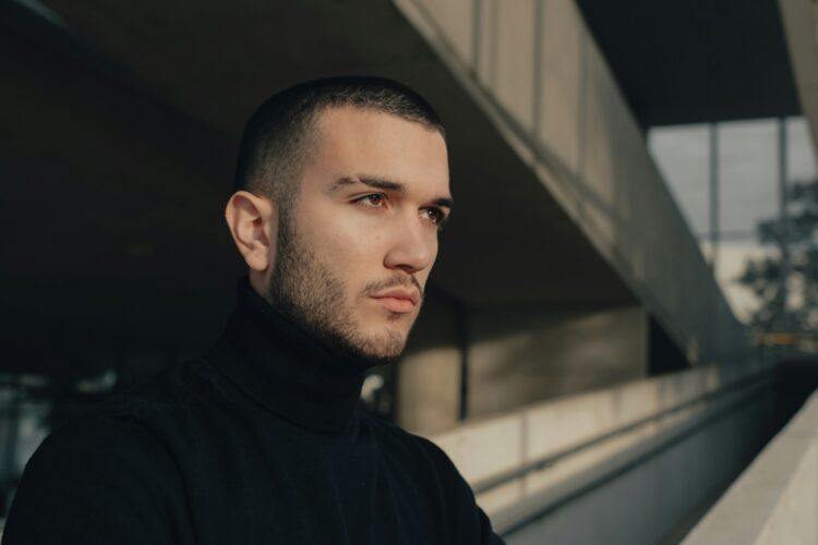 a man in a black turtle neck shirt standing in front of a building