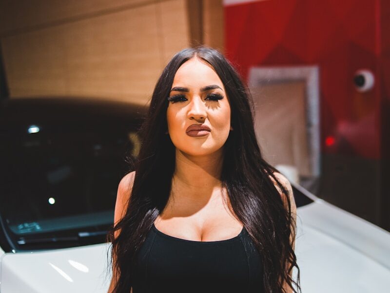 woman in black tank top standing beside white car