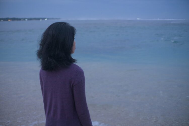 Woman gazes at the ocean at dusk.